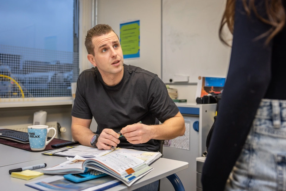 Foto van een docent in zwart t-shirt die opkijkt
