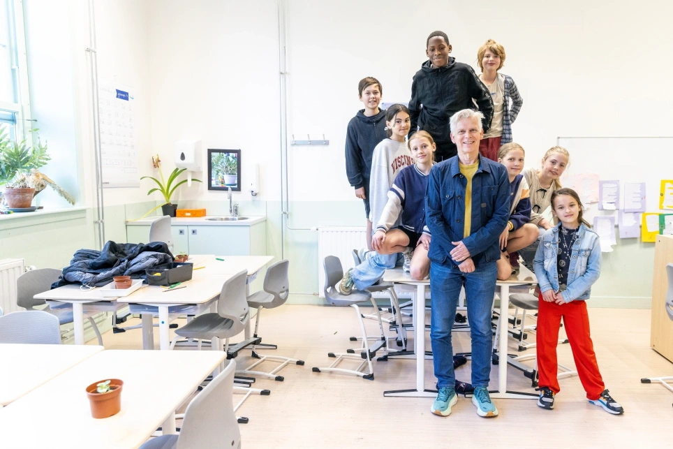 Portret van leraar Jacques van Krugten die met 8 leerlingen van de jenaplanschool in een lokaal staat - beeld bij artikel voor aob.nl/onderwijsblad over het switchen naar een andere school