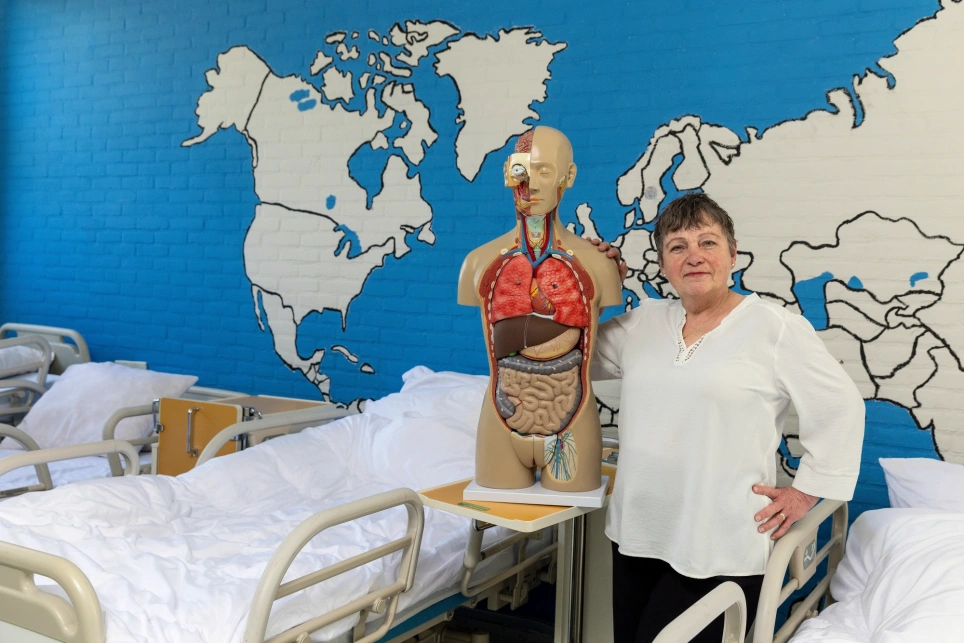 Portret van docent verpleegkunde Jeannine de Jong waarbij ze tussen de ziekenhuisbedden staat en naast een anatomie-torso staat- beeld bij een artikel op aob.nl/onderwijsblad over het switchen naar een nieuwe baan