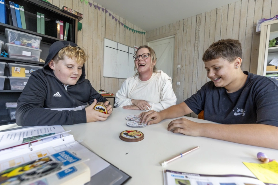 Leerkracht speelt kaarspelletje met twee leerlingen