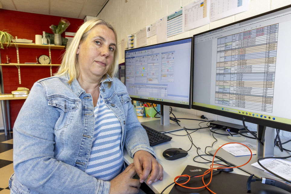 Roostermaker Nicole Groenendijk zit aan haar bureau met twee beeldschermen die aspecten van her schoolrooster laten zien