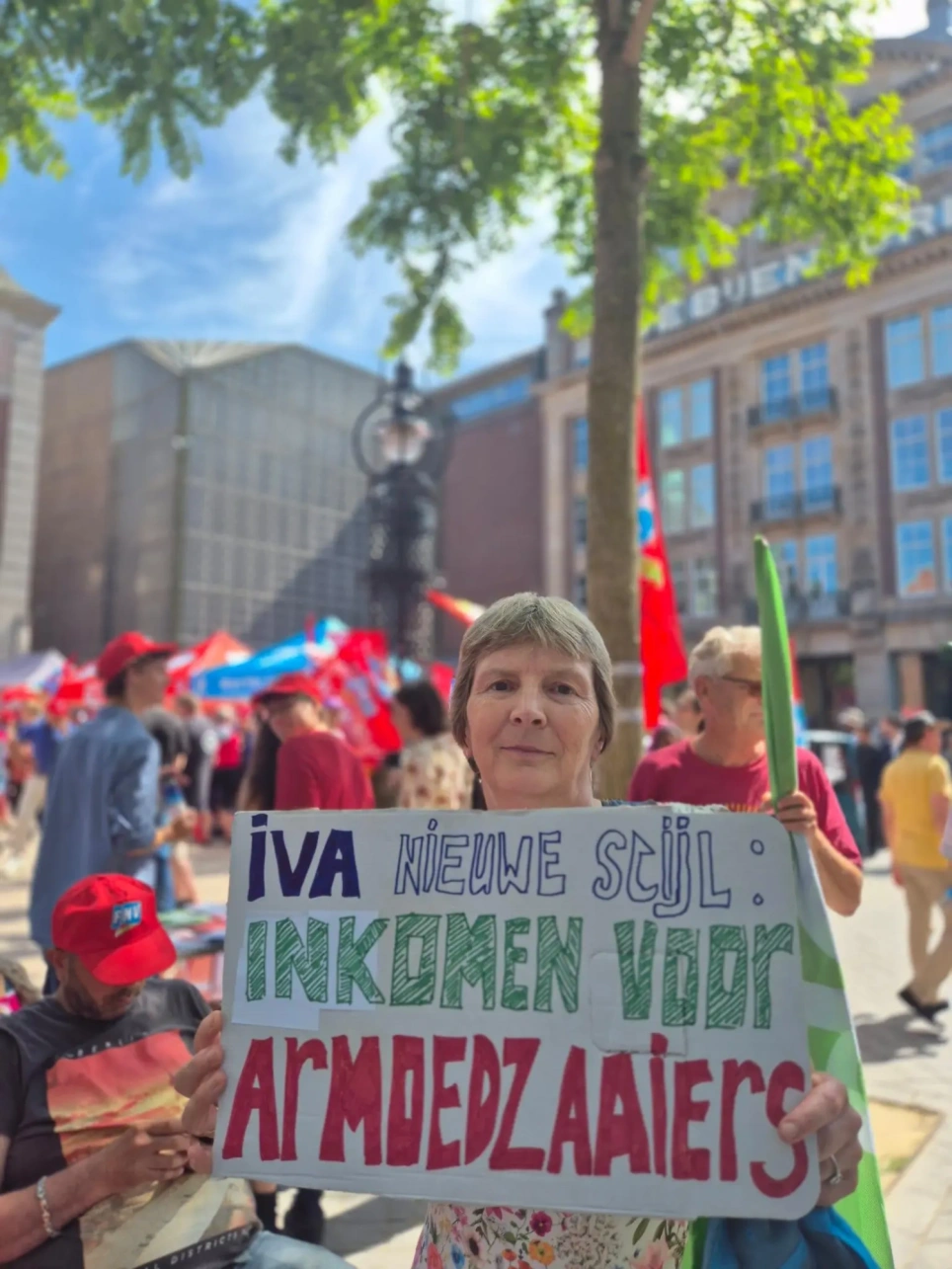 Foto op het Beursplan van Martine de Ket waarbij ze een kartonnen bord vasthoudt met daarop de tekst: 'IVA nieuwe stijl: inkomen voor armoedzaaiers' - beeld bij nieuwsbericht actie sociale zekerheid Amsterdam op AOb.nl
