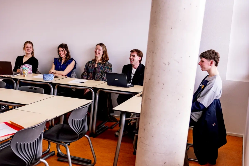 Studenten lachen in een klaslokaal, afbeelding bij artikel op www.aob.nl