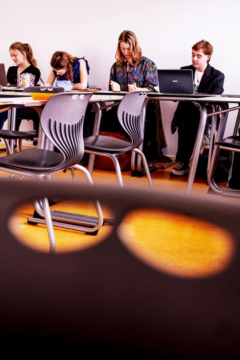 Studenten aan tafeltjes in een klaslokaal, afbeelding bij artikel op www.aob.nl