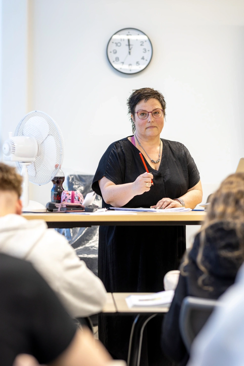 Een foto van economiedocent Rosé Harkes, ze staat voor de klas en houdt een rood potlood vast. Beeld bij artikel op aob.nl/onderwijsblad