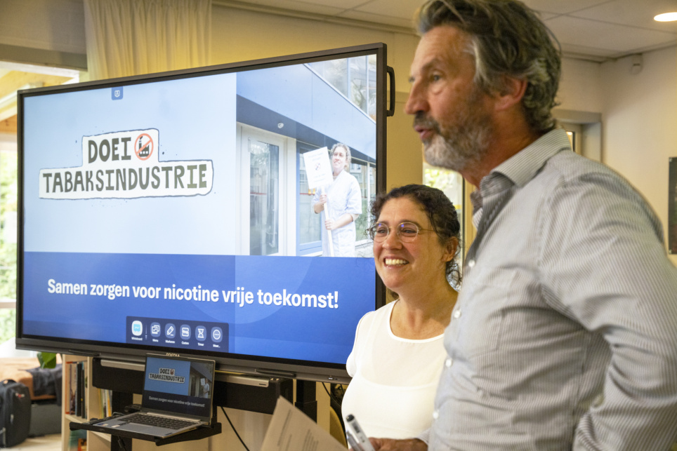Rector Dick Middelhoek van het Laurens Lyceum staat voor een scherm met daarop: 'Doei tabaksindustrie' - beeld bij een artikel op AOb.nl over vapen op middelbare scholen
